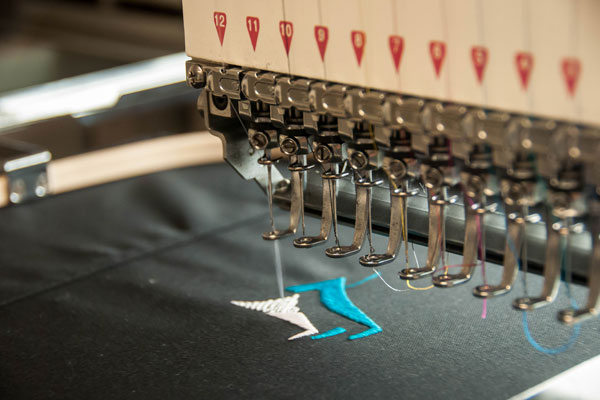 a sewing machine with several needles is embroidering a piece of fabric