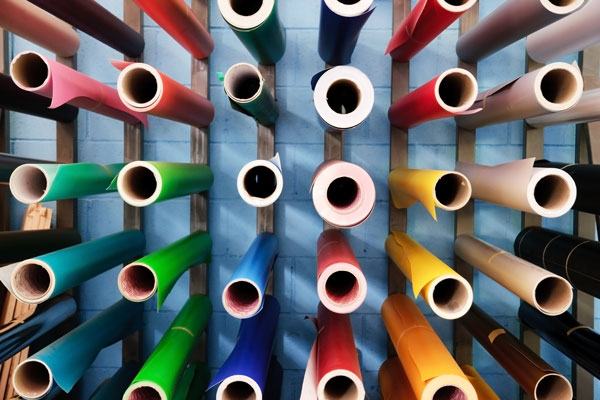 Brightly colored rolls of paper are shown on a rack